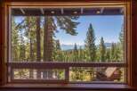 Experience breathtaking lake and mountain views from this stunning property, framed by a lush forest of mature pine trees.