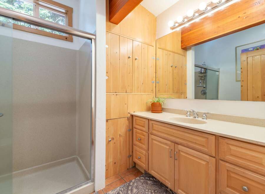 This bathroom features a spacious walk-in shower with a glass door and a light-colored speckled wall.