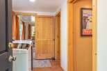 Discover a charming interior featuring a laundry area with a washing machine, complemented by warm orange curtains and natural wood accents throughout.