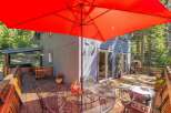 Enjoy outdoor living on this spacious wooden deck, complete with a large red umbrella for shade and a dining set for al fresco meals.