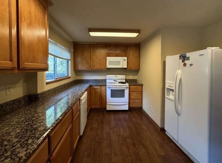 Discover this charming kitchen featuring warm wooden cabinetry and elegant granite countertops.