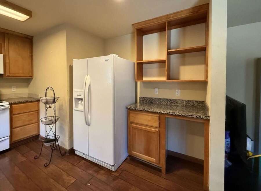 This kitchen features a white refrigerator, a white stove with a microwave above, and ample wooden cabinetry.