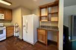 This kitchen features a white refrigerator, a white stove with a microwave above, and ample wooden cabinetry.