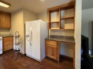 This kitchen features a white refrigerator, a white stove with a microwave above, and ample wooden cabinetry.