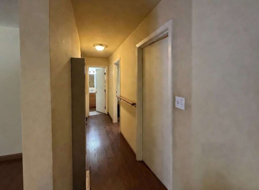 This hallway features warm hardwood floors and neutral-toned walls, creating a welcoming atmosphere.