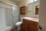 This bathroom features a spacious shower with sliding glass doors, a comfortable toilet, and a wooden vanity with a sink and ample storage.