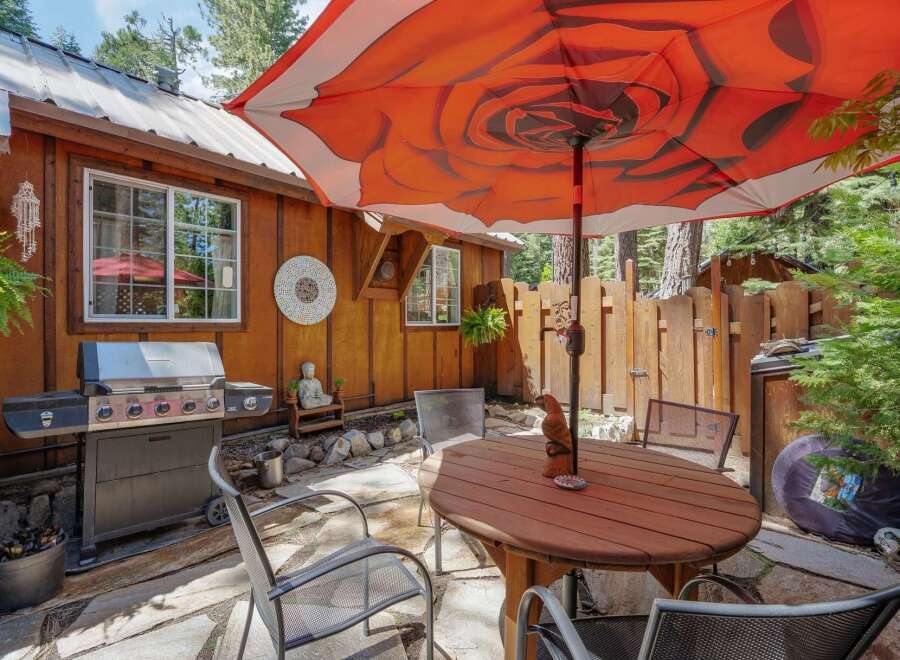 Enjoy outdoor living with this charming patio featuring a spacious grill and a round wooden dining table perfect for al fresco meals.