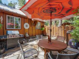 Enjoy outdoor living with this charming patio featuring a spacious grill and a round wooden dining table perfect for al fresco meals.