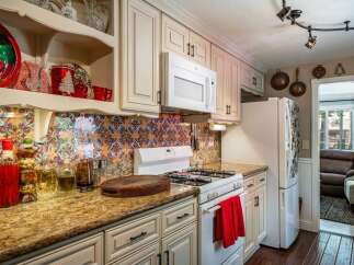 This charming kitchen features a vibrant, patterned backsplash that adds a pop of color to the cream-colored cabinetry.