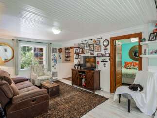 Step into this charming living room, featuring a comfortable brown recliner sofa and a decorative armchair perfect for relaxation.