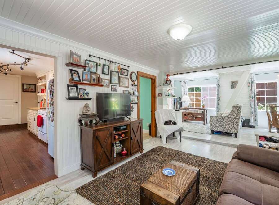 Step into this charming living room, featuring a cozy entertainment center adorned with family photos and a large television.