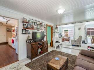 Step into this charming living room, featuring a cozy entertainment center adorned with family photos and a large television.