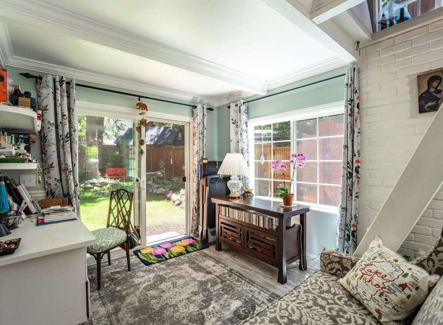 Step into this charming room, bathed in natural light from a large sliding glass door and window, offering a serene view of the backyard.