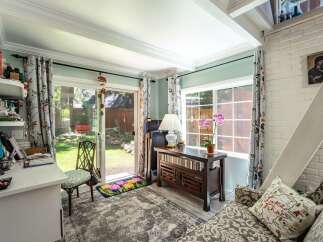 Step into this charming room, bathed in natural light from a large sliding glass door and window, offering a serene view of the backyard.