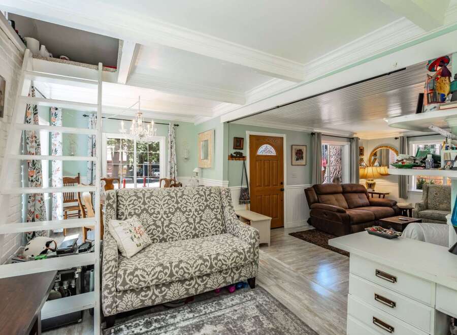 Discover this charming living space featuring a unique lofted area accessible by a ladder, perfect for extra storage or a cozy nook.