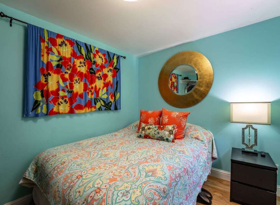 This charming bedroom features a vibrant floral tapestry and a colorful paisley comforter, creating a lively and inviting atmosphere.