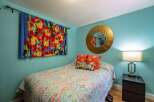 This charming bedroom features a vibrant floral tapestry and a colorful paisley comforter, creating a lively and inviting atmosphere.