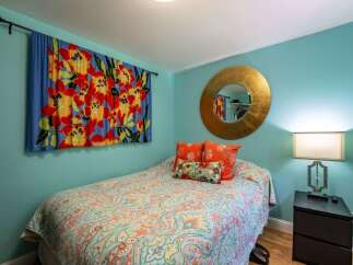 This charming bedroom features a vibrant floral tapestry and a colorful paisley comforter, creating a lively and inviting atmosphere.