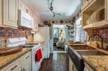 This charming kitchen boasts a unique backsplash and a deep copper sink, perfect for culinary enthusiasts.