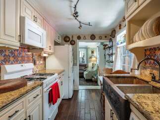 This charming kitchen boasts a unique backsplash and a deep copper sink, perfect for culinary enthusiasts.