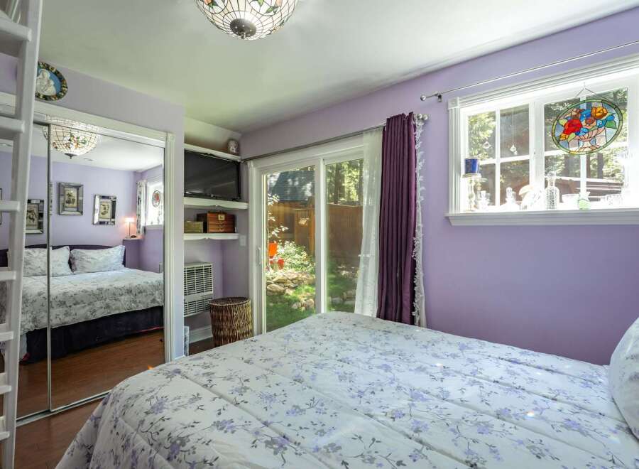 This charming bedroom features a comfortable queen-size bed with a floral comforter, complemented by a large mirrored closet.