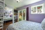 This charming bedroom features a comfortable queen-size bed with a floral comforter, complemented by a large mirrored closet.
