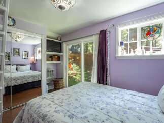 This charming bedroom features a comfortable queen-size bed with a floral comforter, complemented by a large mirrored closet.