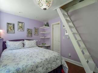 Discover this charming bedroom featuring a comfortable queen-size bed with a floral comforter and a stylish purple headboard.