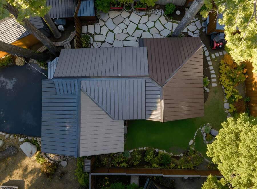 Experience modern living with this stunning aerial view showcasing a unique architectural design featuring a multi-toned metal roof.