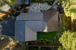 Experience modern living with this stunning aerial view showcasing a unique architectural design featuring a multi-toned metal roof.