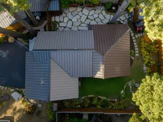 Experience modern living with this stunning aerial view showcasing a unique architectural design featuring a multi-toned metal roof.