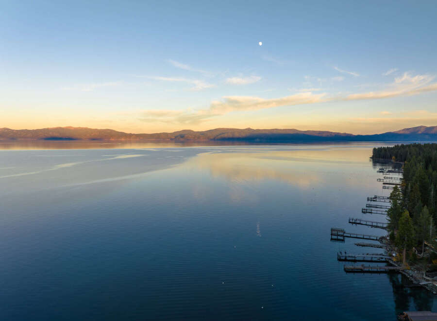 Experience serene lakefront living with this stunning aerial view of a tranquil lake at sunset.