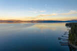 Experience serene lakefront living with this stunning aerial view of a tranquil lake at sunset.