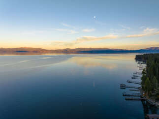 Experience serene lakefront living with this stunning aerial view of a tranquil lake at sunset.