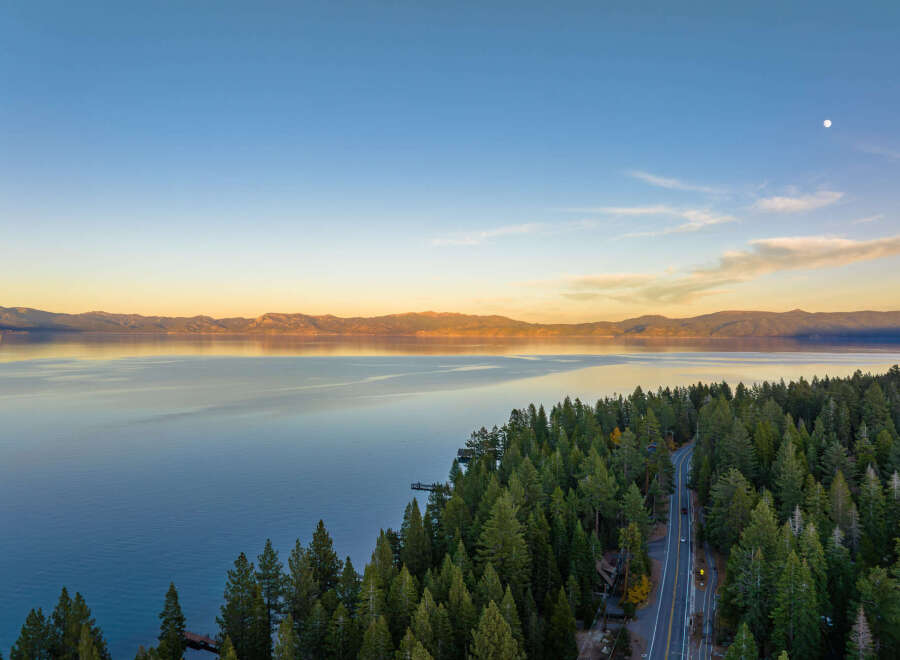 Experience breathtaking lakefront living with this stunning aerial view of a property nestled amidst a lush pine forest.
