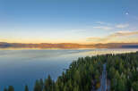Experience breathtaking lakefront living with this stunning aerial view of a property nestled amidst a lush pine forest.