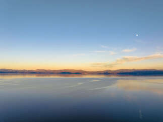 Experience breathtaking sunset views over a serene lake, with majestic mountains forming a stunning backdrop.