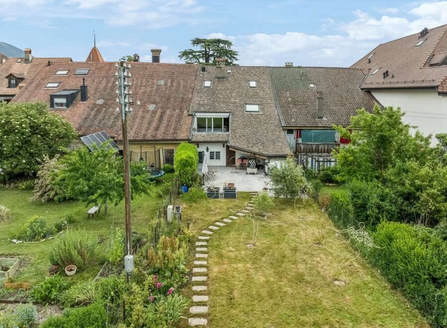 Discover this charming property featuring a spacious backyard with a stone pathway leading through a lush garden.