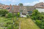 Discover this charming property featuring a spacious backyard with a stone pathway leading through a lush garden.