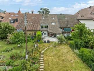 Discover this charming property featuring a spacious backyard with a stone pathway leading through a lush garden.