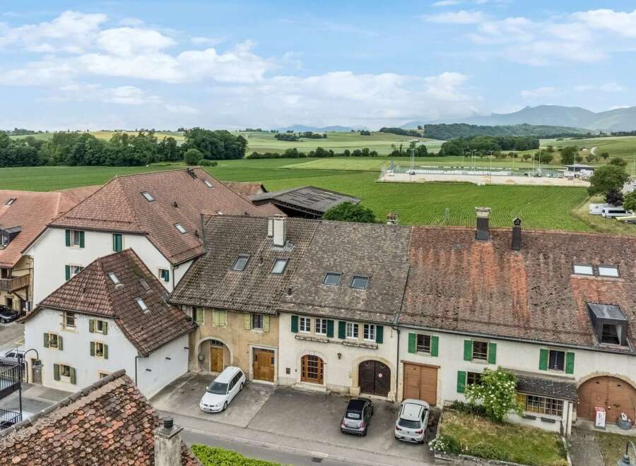 Discover this charming property featuring a classic tiled roof and traditional shutters, set against a backdrop of picturesque green fields and rolling hills.