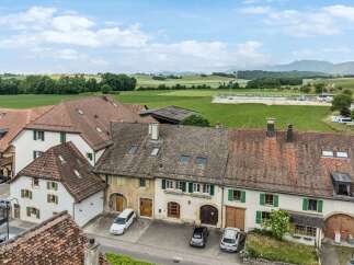 Discover this charming property featuring a classic tiled roof and traditional shutters, set against a backdrop of picturesque green fields and rolling hills.