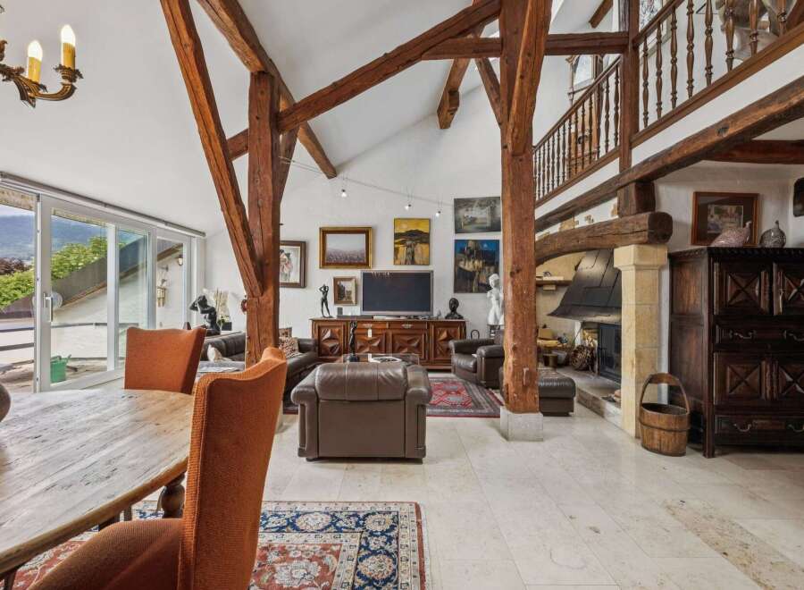 Experience rustic charm and modern comfort in this stunning living space, featuring exposed wooden beams and a grand stone fireplace.