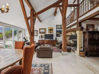 Experience rustic charm and modern comfort in this stunning living space, featuring exposed wooden beams and a grand stone fireplace.