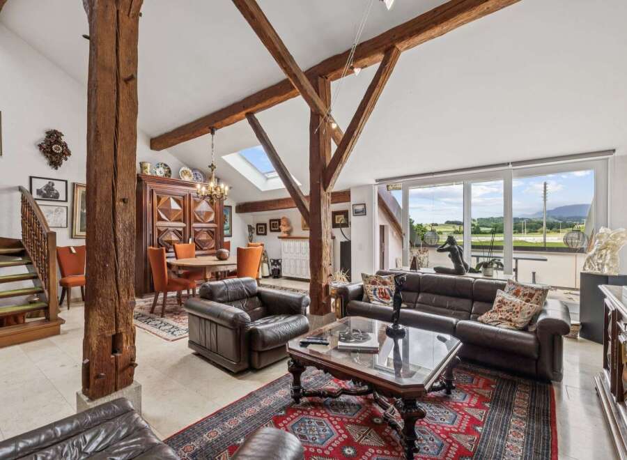 Experience rustic charm and modern comfort in this spacious living area, featuring exposed wooden beams and a grand fireplace.
