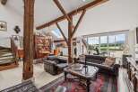 Experience rustic charm and modern comfort in this spacious living area, featuring exposed wooden beams and a grand fireplace.