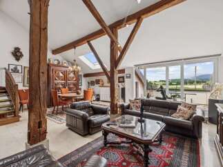 Experience rustic charm and modern comfort in this spacious living area, featuring exposed wooden beams and a grand fireplace.