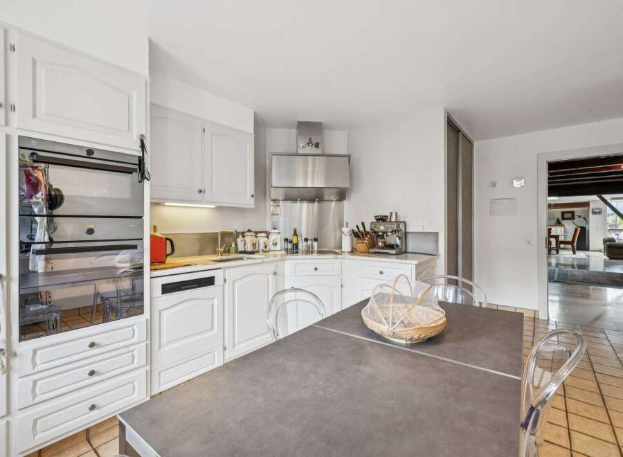 This spacious kitchen features a sleek stainless steel range hood and a built-in oven, perfect for any home chef.