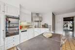 This spacious kitchen features a sleek stainless steel range hood and a built-in oven, perfect for any home chef.
