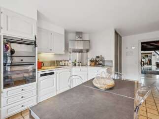 This spacious kitchen features a sleek stainless steel range hood and a built-in oven, perfect for any home chef.